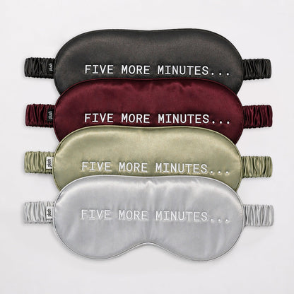 Four silk sleep masks in charcoal, burgundy, olive green and silver, featuring the words “FIVE MORE MINUTES…”.