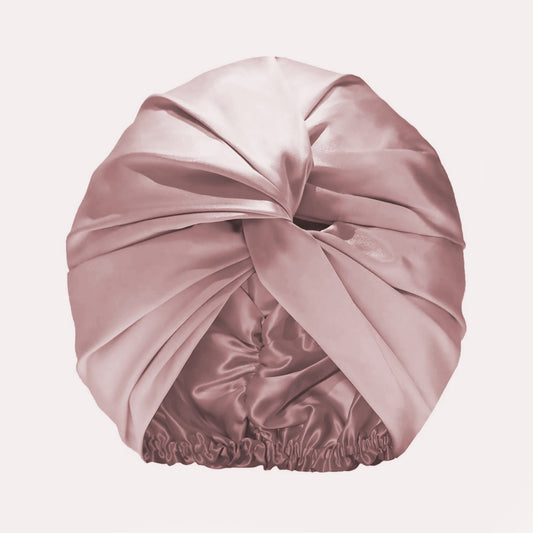 Pink silk sleep bonnet with a twisted front and an elasticated back.
